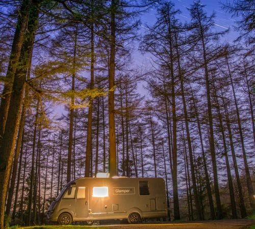 GlamperRV luxury motorhome parked at night in the woods